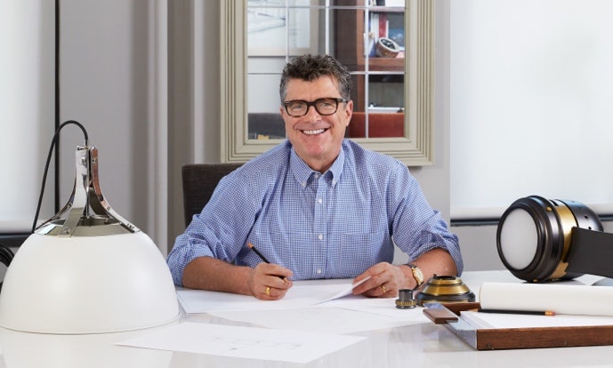 A person sitting at a desk smiling Description automatically generated